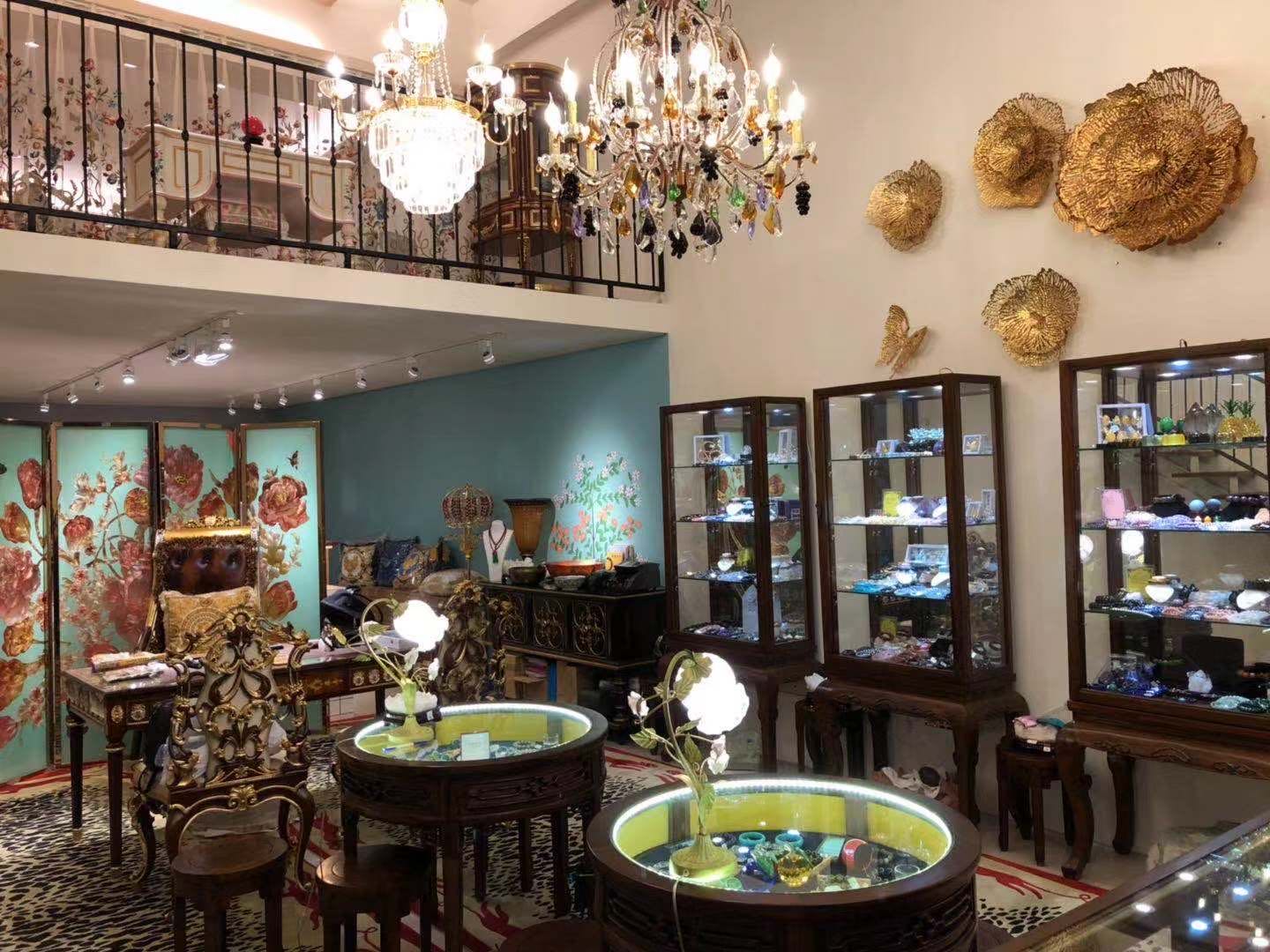 媧石皇家台北店內：水晶吊燈、金色花朵壁飾、木框玻璃展示櫃與圓形展示桌